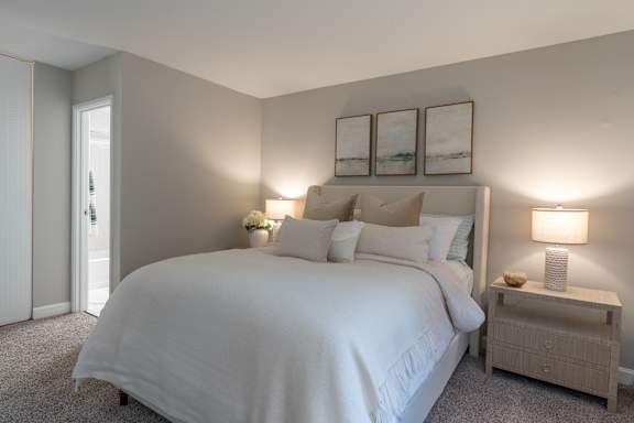A bedroom with a large bed and two lamps.