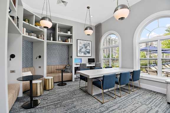 A modern office space with a large desk, chairs, and a balcony with a view of the outside.