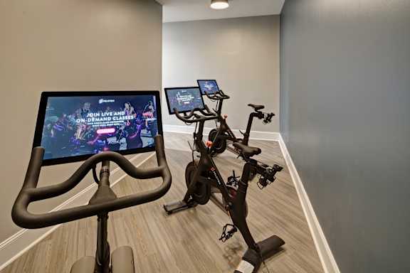 A room with a stationary bike and a screen showing a video game.