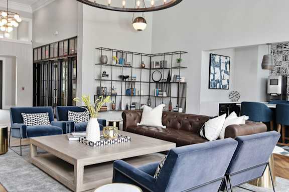 A modern living room with a brown leather couch and blue chairs.