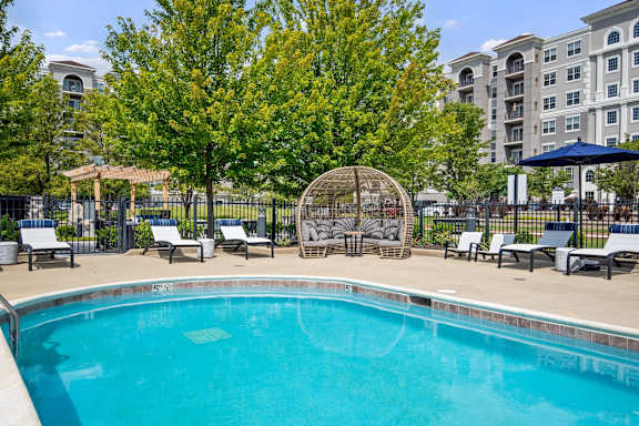 A swimming pool surrounded by trees and chairs.