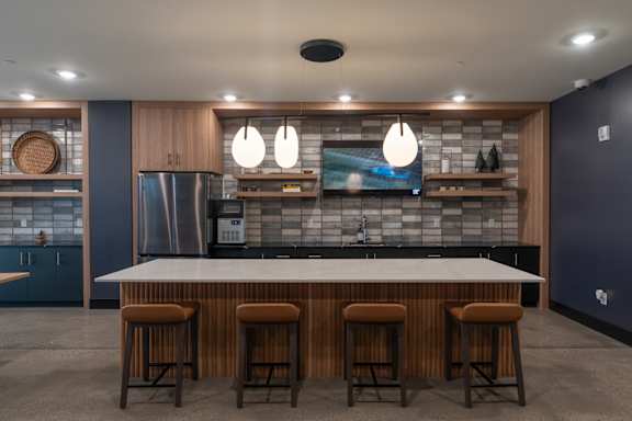 A modern kitchen with a bar area and wooden stools.