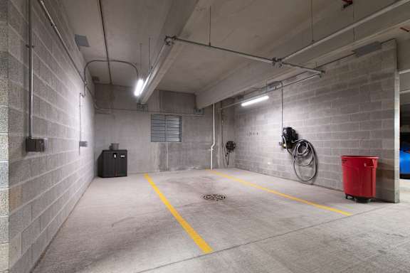 A parking garage with a red trash can and a yellow line on the floor.