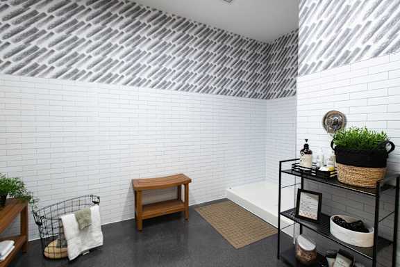 A bathroom with a white tiled wall and a black and white striped ceiling.