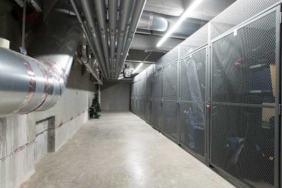 A long hallway with pipes on the ceiling and a Christmas tree in the corner.