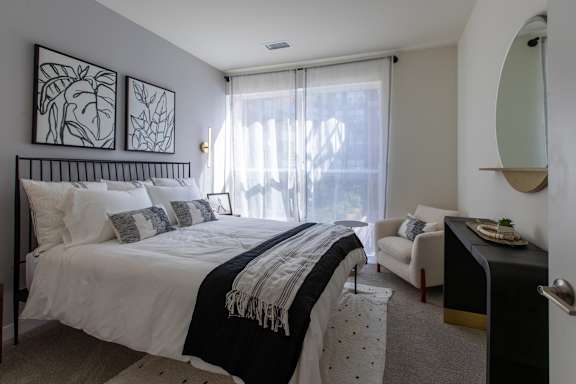 A bedroom with a large bed and a chair.