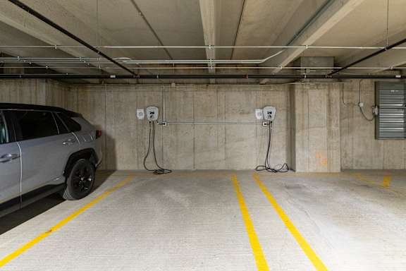 A car is parked in a parking garage with yellow lines on the floor.