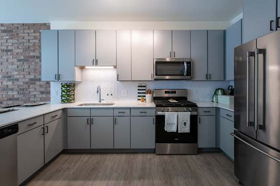 A modern kitchen with stainless steel appliances and wooden flooring.