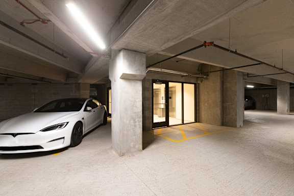 A Tesla car is parked in a parking garage.