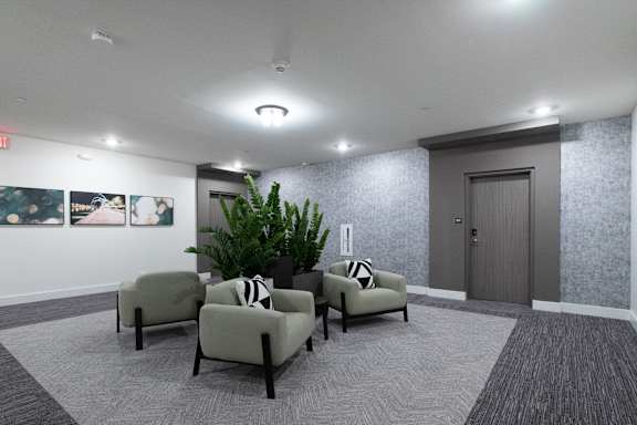 A waiting room with grey chairs and a grey carpet.