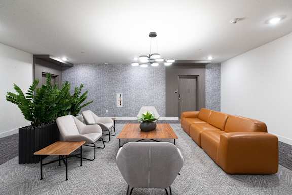 A grey sofa sits in a room with a wooden table and a potted plant.