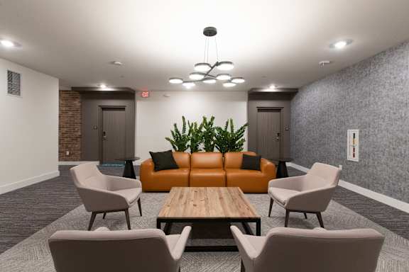 A modern waiting room with a wooden table and grey chairs.