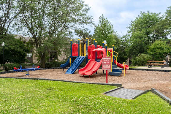 A playground with a red slide and a yellow safety sign.