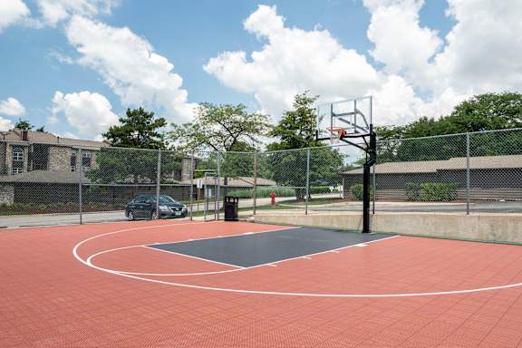 A basketball court with a red surface and a basketball hoop.