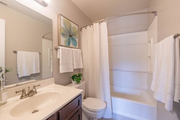 A white bathroom with a toilet, sink, and shower.
