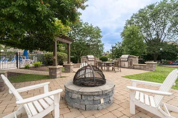 A backyard with a fire pit and chairs.
