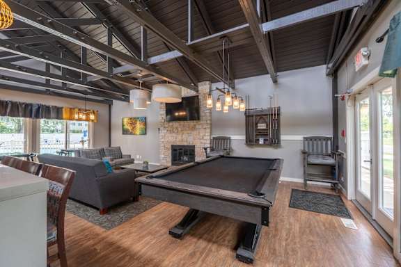 A pool table is in the middle of a room with a fireplace and a couch.