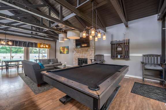 A pool table is in the middle of a room with a fireplace and a couch.