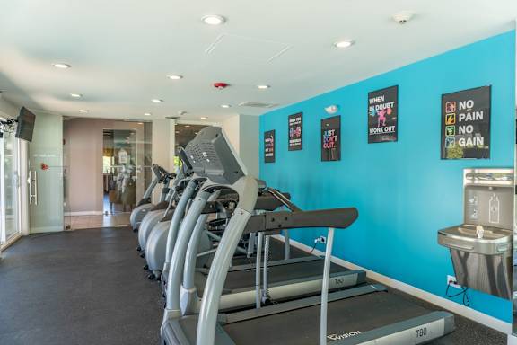 A gym with treadmills and a wall of posters.