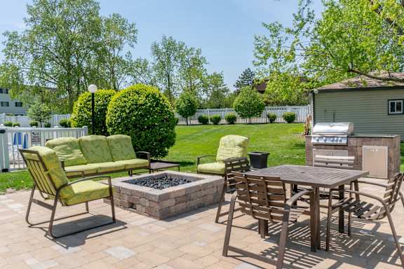 A patio with a table, chairs, and a fire pit.