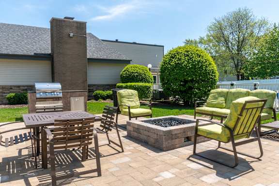 A patio with a table, chairs, and a fire pit.