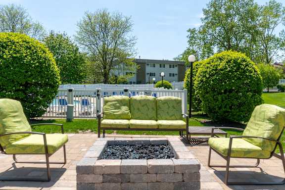 A patio with a fire pit and chairs.