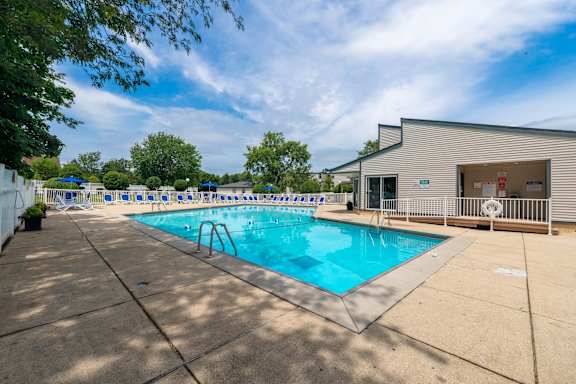 A large outdoor swimming pool with a diving board and a building in the background.