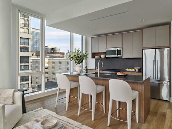A modern kitchen with white chairs and a view of the city.