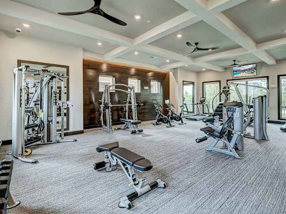 A spacious gym with a variety of equipment including a bench press, a squat rack, and a treadmill.
