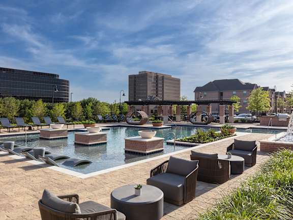 A pool area with lounge chairs and a fountain.
