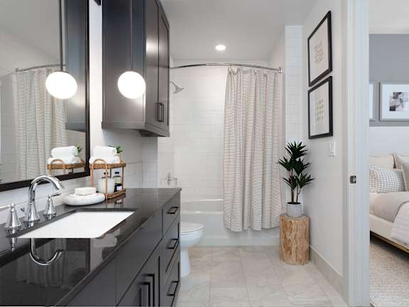 A bathroom with a black countertop and a white sink.