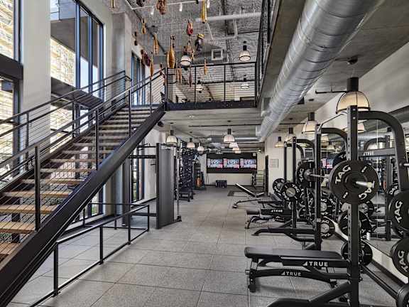 A gym with a staircase, weights, and exercise equipment.