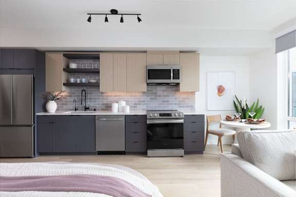 A modern kitchen with a refrigerator, oven, and microwave.