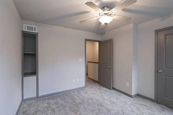 A room with a ceiling fan and a door.