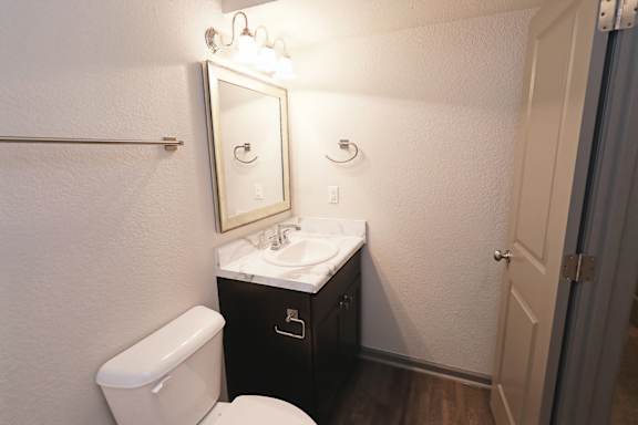 A bathroom with a toilet, sink, and mirror.