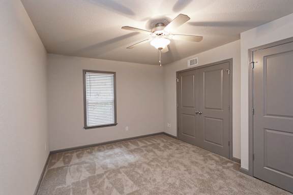 A room with a ceiling fan and a window with blinds.