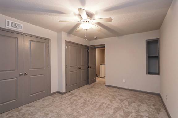 A room with a ceiling fan and carpeted floor.
