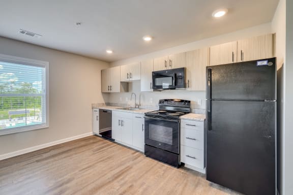 a kitchen with white cabinets and black appliances and a black refrigerator at MacArthur Park, Augusta