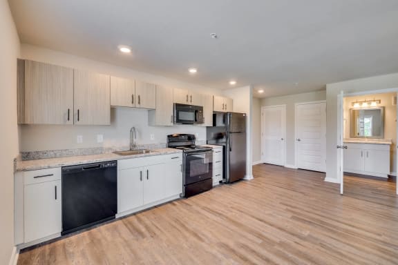 a kitchen with white cabinets and a black stove and refrigerator at MacArthur Park, Augusta