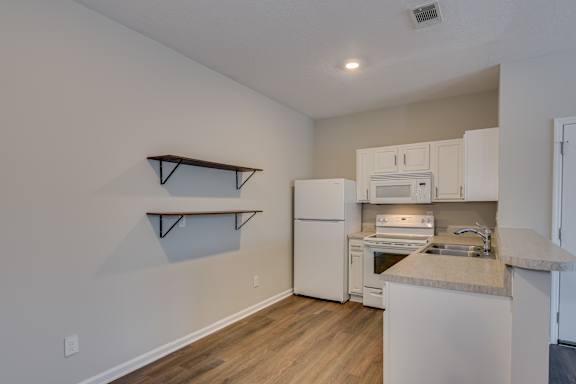 Kitchen with shelves and white appliances at The Vista Apartments &amp; Townhomes, Warrenville, SC, 29851