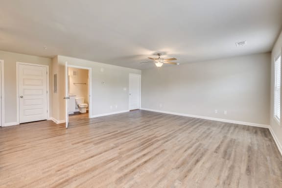 an empty living room with a ceiling fan and a door to a bathroom at MacArthur Park, Augusta