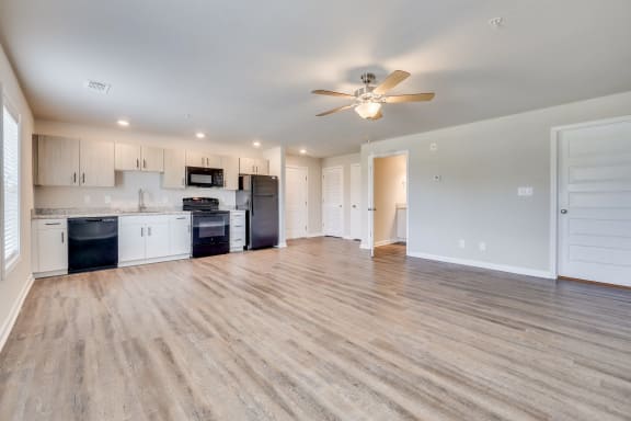an empty living room with a kitchen and a ceiling fan at MacArthur Park, Augusta