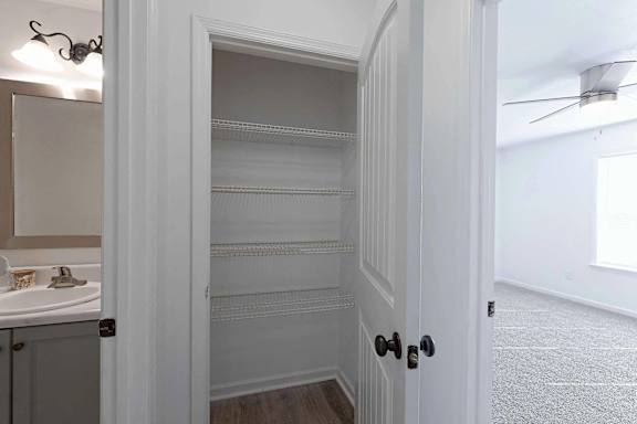 a bathroom with an open door and a closet with shelves at Sterlington Apartments, Georgia
