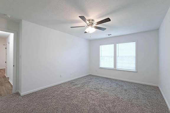an empty living room with a ceiling fan and a window at Sterlington Apartments, Grovetown
