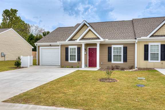 a beige house with a red door and a front yard at The Vista Apartments &amp; Townhomes, Warrenville, SC, 29851