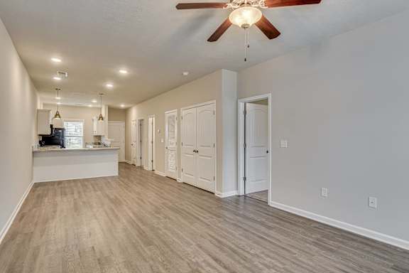 Empty living room with ceiling fan and wood-look flooring at Barrington Apartments, South Carolina, 29649