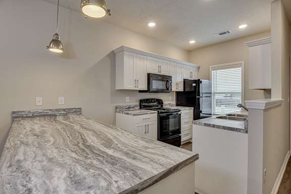 a kitchen with a marble counter top and a black stove and refrigerator at Barrington Apartments, Greenwood, SC, 29649