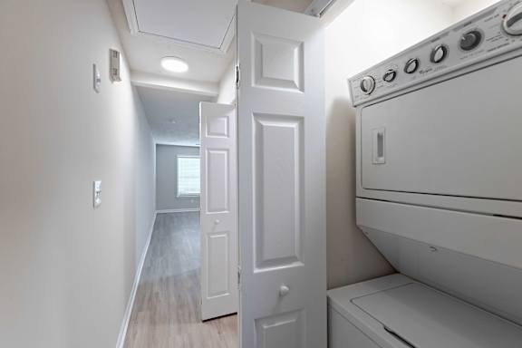 A white door is in a hallway with a washer and dryer on the wall at Sanctuary Apartments and Townhomes, Augusta, GA