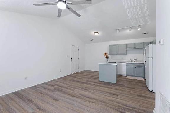 an empty living room with a kitchen and a ceiling fan at Sterlington Apartments, Grovetown, GA