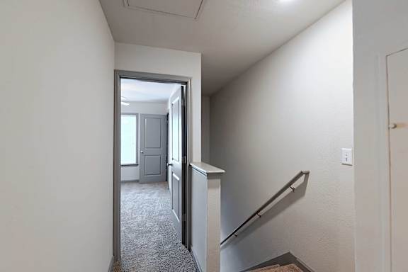 A hallway with a staircase leading to a second floor.